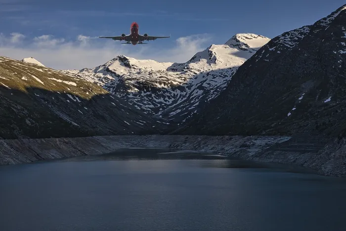 Framed Print : Aeroplane flying over a mountain lake with snow-covered peaks under a blue sky