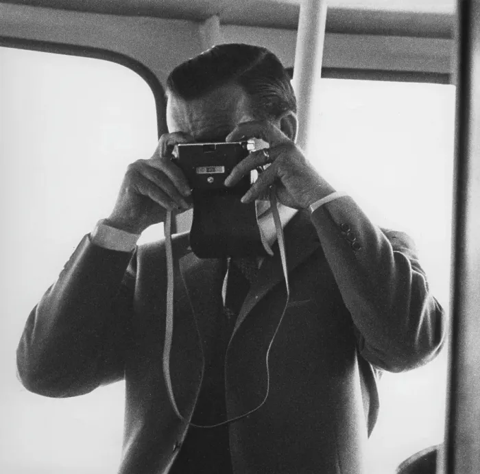 Framed Print : Amateur photographer in the 1960s. So much an amateur that he is holding his camera the wrong way, looking into the lens on the front instead of in the view-finder on the back of the camera. By doing this he will take a picture of himself Framed Print : Amateur photographer in the 1960s. So much an amateur that he is holding his camera the wrong way, looking into the lens on the front instead of in the view-finder on the back of the camera. By doing this he will take a picture of himself