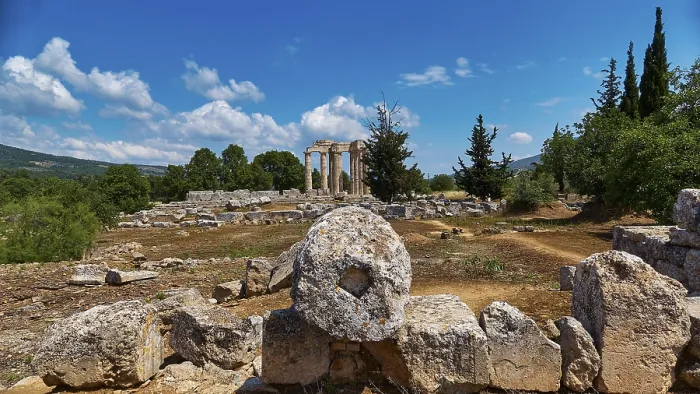 Framed Print : Ancient temple columns in an open field with surrounding trees and mountains in the background
