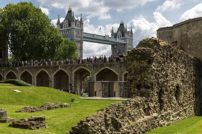 Framed Print : Arched stone structure with tourists under a partly cloudy sky at The Tower of London with Tower Bridge