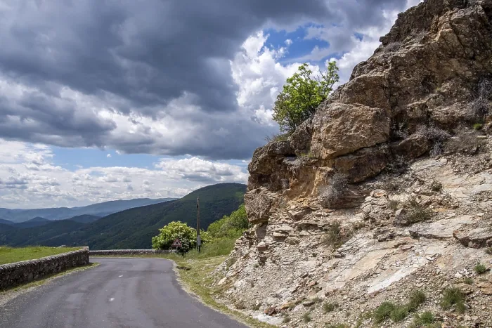 Framed Print : Asphalt road curving around a rocky cliff