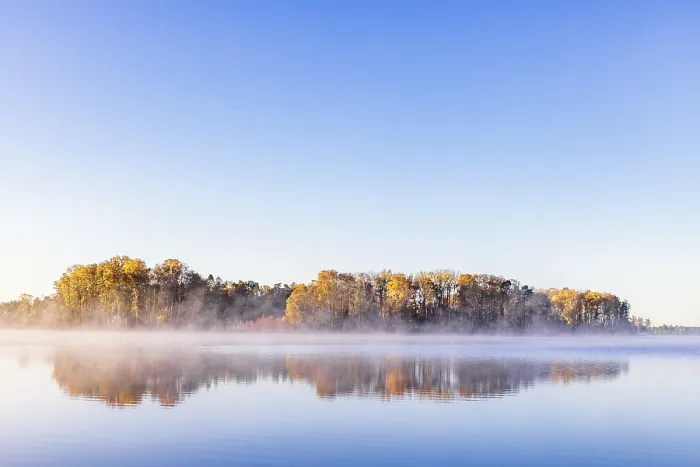 Framed Print : Autumn colors on the trees at a lake with water reflections and mist
