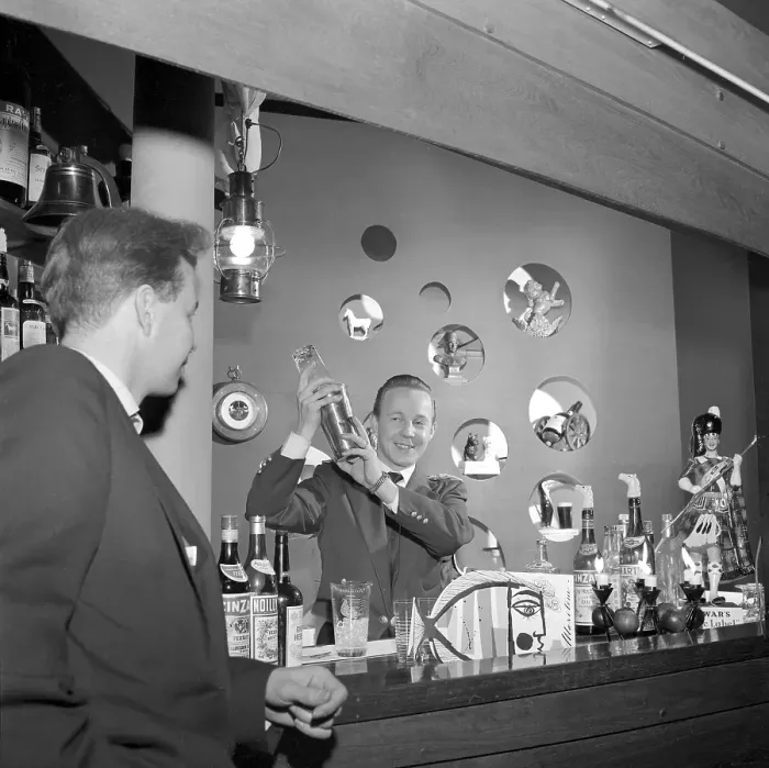 Framed Print : Bar in the 1950s. A bartender is mixing drinks behind the bar counter