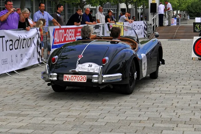 Framed Print : Black classic car from behind with audience and atmosphere of the event