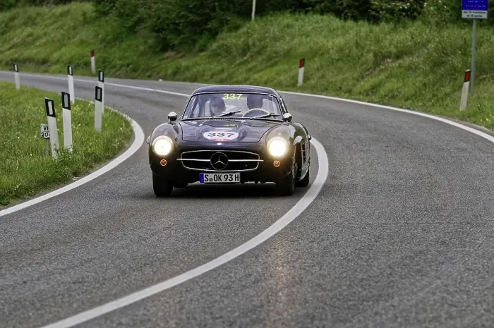 Framed Print : Black classic car drives through a picturesque winding road