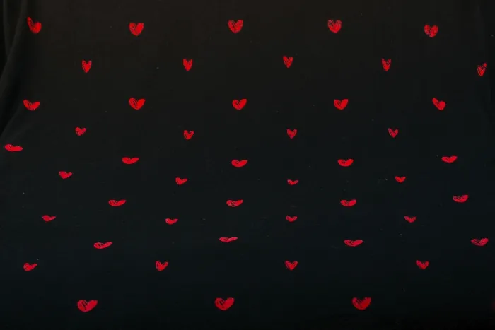 Framed Print : Black fabric background with red hearts shapes