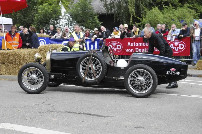 Framed Print : A black historic racing car is pushed by a man at a classic car event