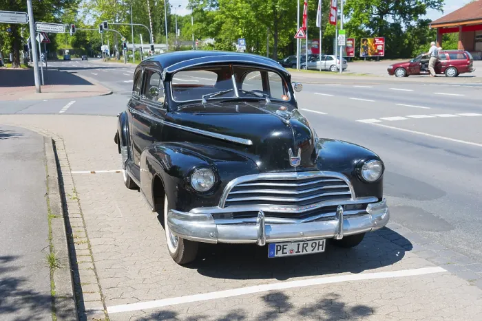 Framed Print : A black vintage car is parked in a car park on a road