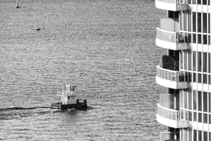 Framed Print : A black and white image of a boat on water next to a modern building in Toronto