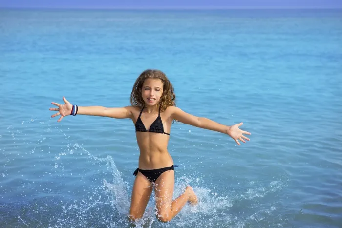 Framed Print : Blue beach kid girl with bikini jumping and running splashing water