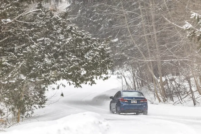 Framed Print : A blue car travels down a snow-covered road in a forest