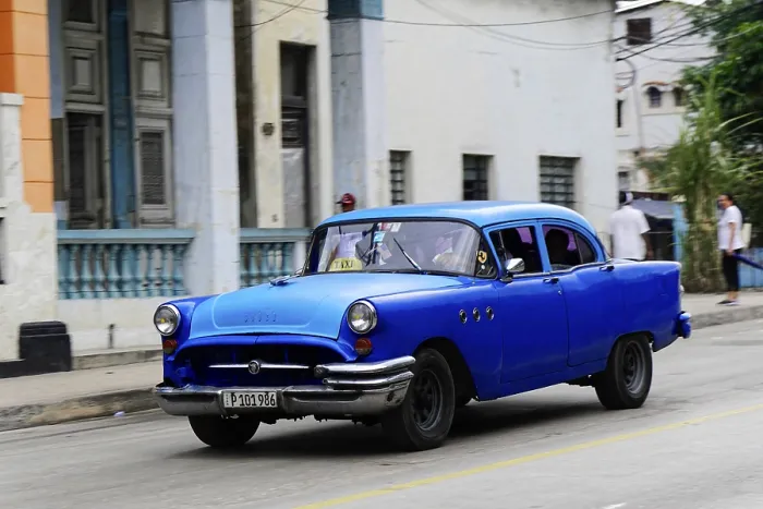 Framed Print : Blue classic car on a road surrounded by colonial architecture