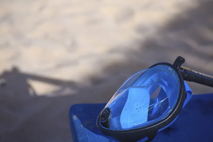 Framed Print : Blue diving mask resting on a surface with sandy beach in the background Framed Print : Blue diving mask resting on a surface with sandy beach in the background