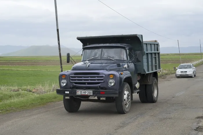 Framed Print : A blue lorry with a trailer drives on a country road surrounded by green fields and mountains