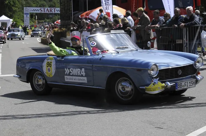 Framed Print : A blue open-top vintage rally car with a smiling driver in front of spectators Framed Print : A blue open-top vintage rally car with a smiling driver in front of spectators