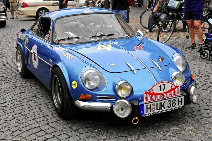 Framed Print : A blue Renault classic car with racing stripes drives through the city