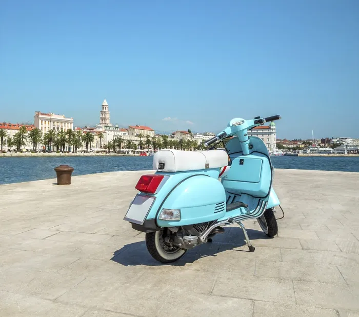 Framed Print : Blue vintage scooter stands on the waterfront on the background the city and the cruise ships in the sunny weather