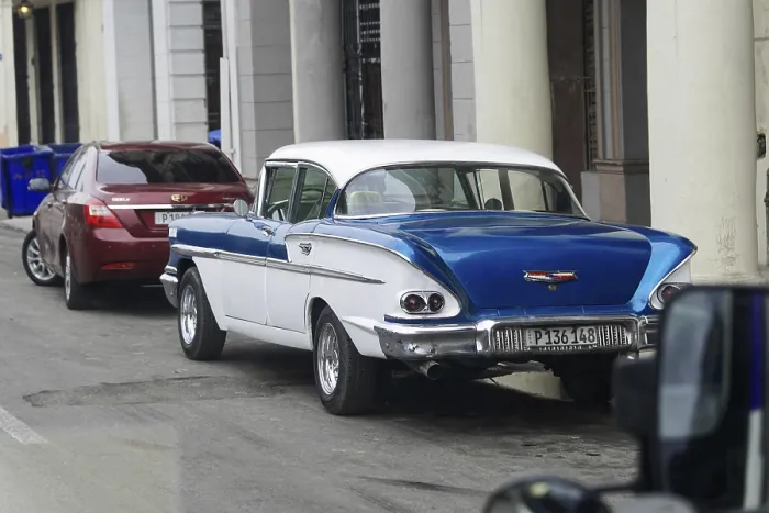 Framed Print : Blue and white classic car parked next to modern cars in the city