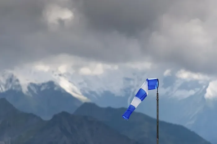 Framed Print : Blue and white windsock on the summit of the Nebelhorn in front of the mountain range with dark clouds