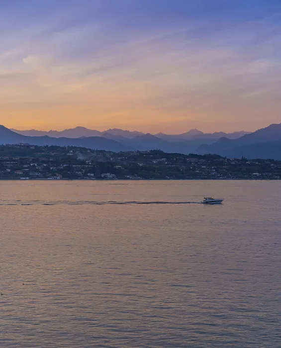 Framed Print : A boat in the sunset with the silhouettes of the mountains in the background on Lake Garda