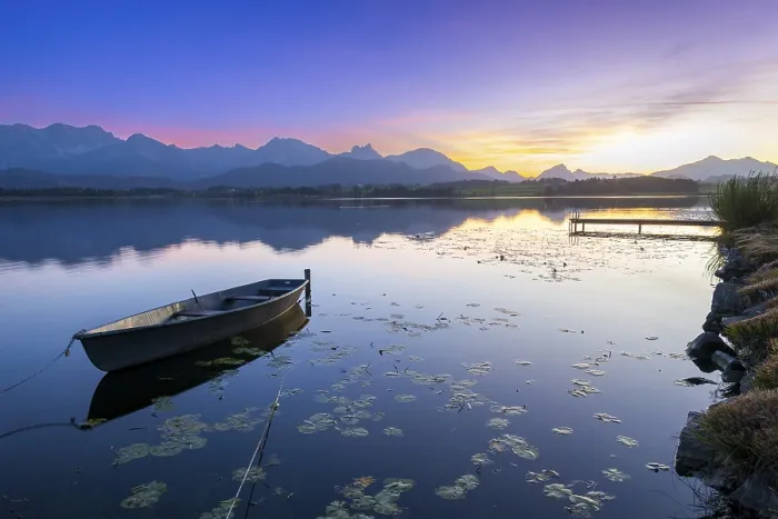 Framed Print : Boats at a jetty on a calm lake at sunset with mountains in the background