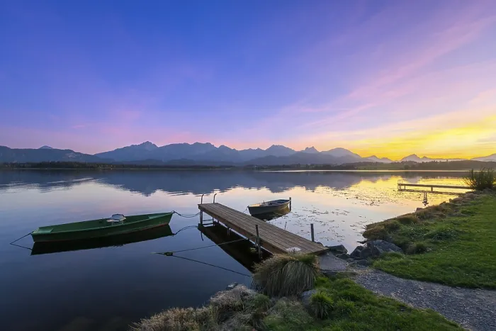 Framed Print : Boats at a jetty on a calm lake at sunset with mountains in the background Framed Print : Boats at a jetty on a calm lake at sunset with mountains in the background
