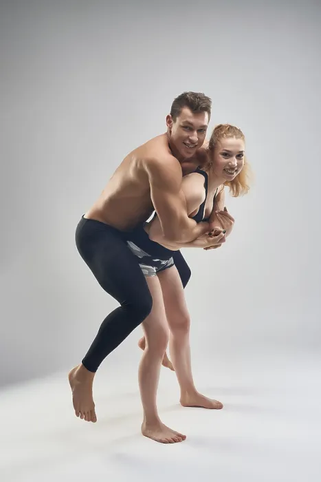 Framed Print : Full body tight man in black tights flatting on back of slim young female in black shorts looking at camera