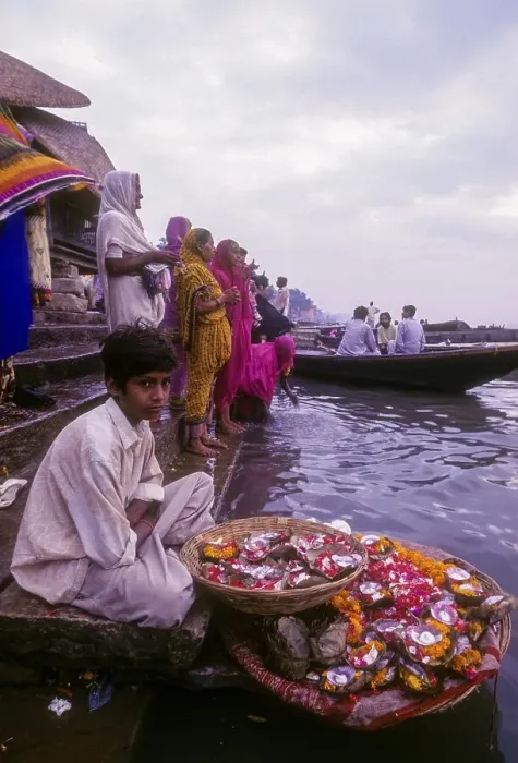 Framed Print : A boy selling mari gold flowers used in workship sitting in front of River Ganga Ganges at Varanasi Benaras