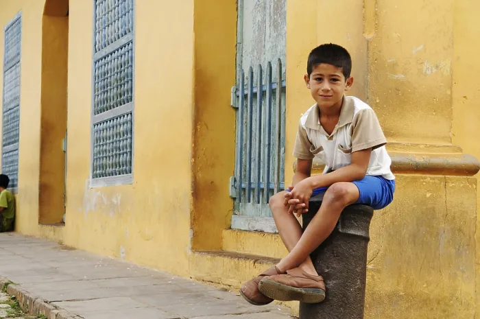 Framed Print : Boy sitting on a cannon, bollard in the historic centre of Trinidad Framed Print : Boy sitting on a cannon, bollard in the historic centre of Trinidad