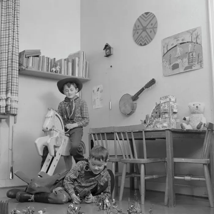 Framed Print : Boys in the 1950s. Two boys in their play room are dressed as cowboys. One is riding a wooden horse and one is playing with figures of cowboys and indians on the floor. Sweden 1953 Conard ref 2273