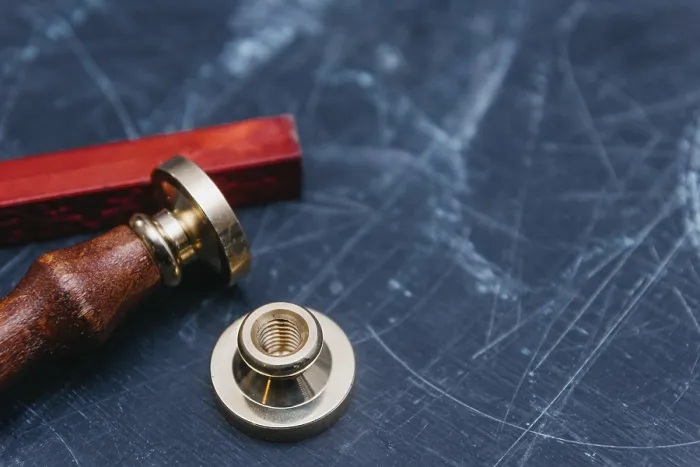 Framed Print : Brass seal with red wax on a textured dark background