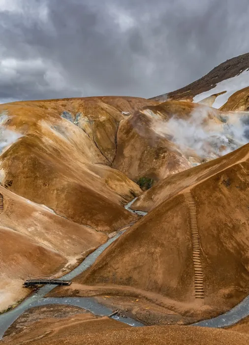 Framed Print : Bridge over steaming stream between colourful rhyolite mountains with snowfields