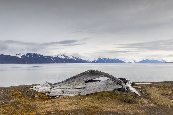 Framed Print : Broken wooden boat in front of mountain range