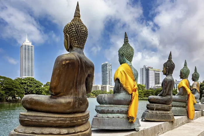 Framed Print : Buddha statues in bronze with yellow cloths in front of skyscrapers and water