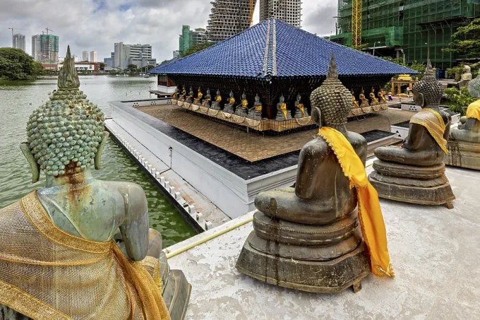 Framed Print : Buddha statues with yellow cloths sit in front of a modern cityscape on the water Framed Print : Buddha statues with yellow cloths sit in front of a modern cityscape on the water