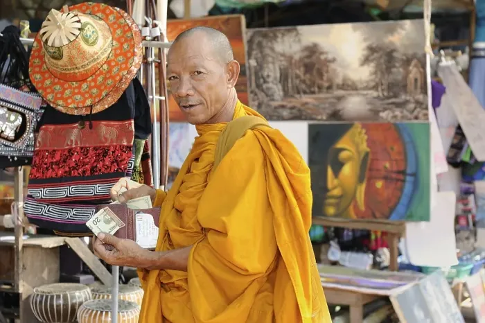 Framed Print : Buddhist monk buying statues of saints from a souvenir shop on the grounds of Angkor Wat