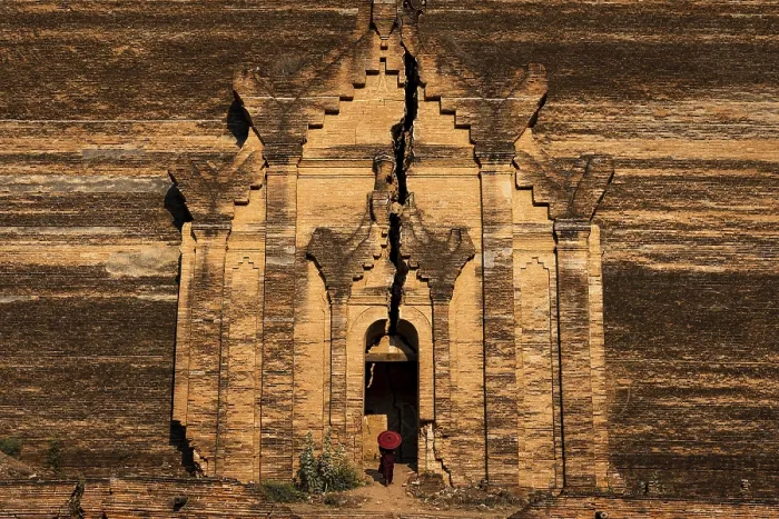 Framed Print : Buddhist monk stands with red umbrella in the entrance of Mingun Pagoda