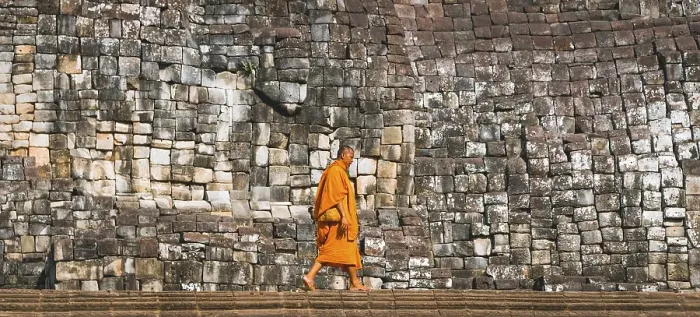 Framed Print : Buddhist monk walks in front of old stone wall Framed Print : Buddhist monk walks in front of old stone wall
