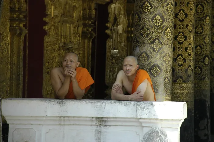 Framed Print : Buddhist monks leaning against a wall of Wat Mai Suwannaphumaham