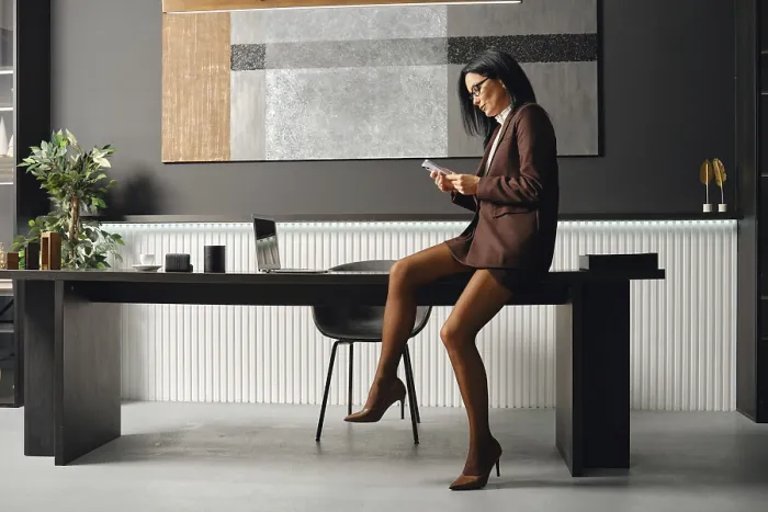 Framed Print : Serious business woman in a brown suit sits on a desk Framed Print : Serious business woman in a brown suit sits on a desk