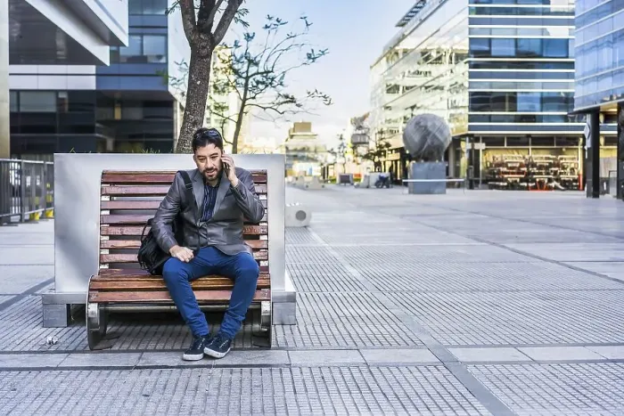 Framed Print : A businessman is talking on the cell phone while sitting on a bench in the street
