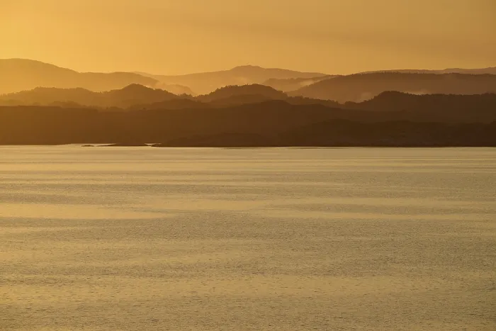 Framed Print : Calm atmosphere over the sea, hills and an orange sunrise