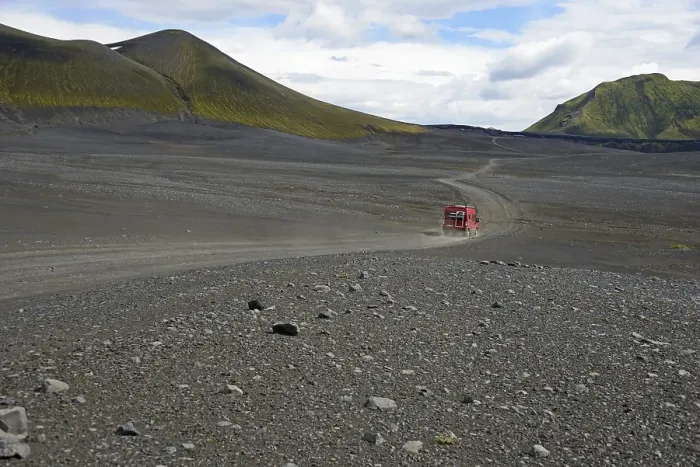 Framed Print : Caravan on dirt road in barren volcanic landscape