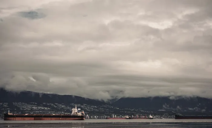 Framed Print : Cargo ships on the ocean with a mountainous backdrop under a cloudy sky Framed Print : Cargo ships on the ocean with a mountainous backdrop under a cloudy sky
