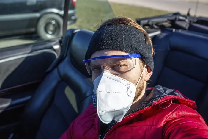 Framed Print : Casually dressed man wearing a face mask and goggles in a car on a sunny day