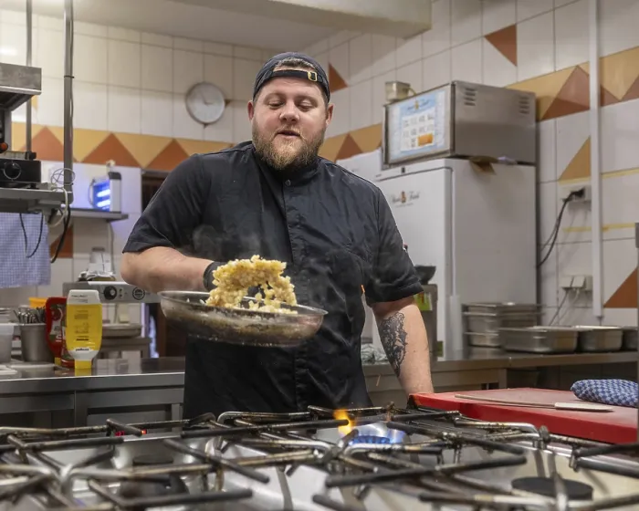 Framed Print : A chef in a black uniform expertly prepares a dish in a professional kitchen