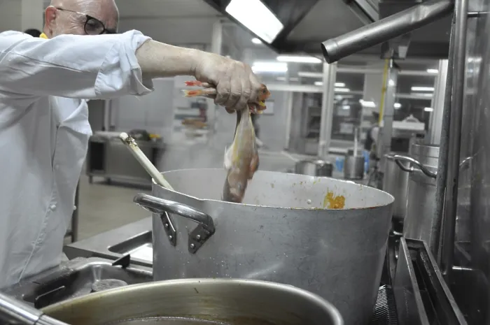 Framed Print : Chef holding fish over a steaming pot in a professional kitchen