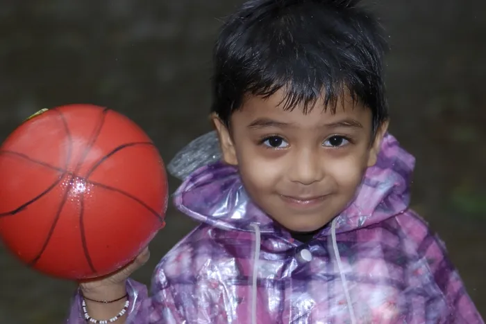 Framed Print : Child Playing in the Rain with ball, India