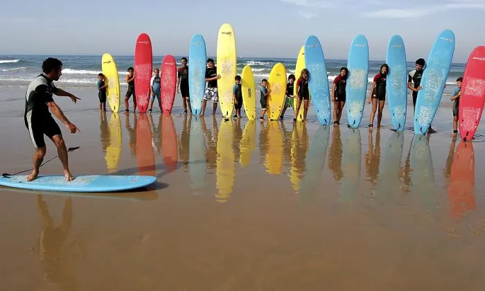 Framed Print : Children with surfboards listen to a teacher during a surf lesson