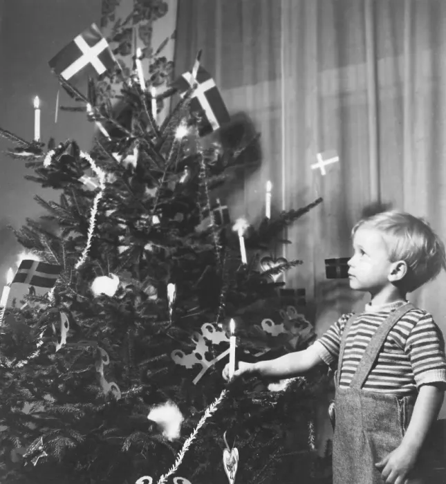 Framed Print : Christmas in the 1940s. A boy is standing by the decorated christmas tree